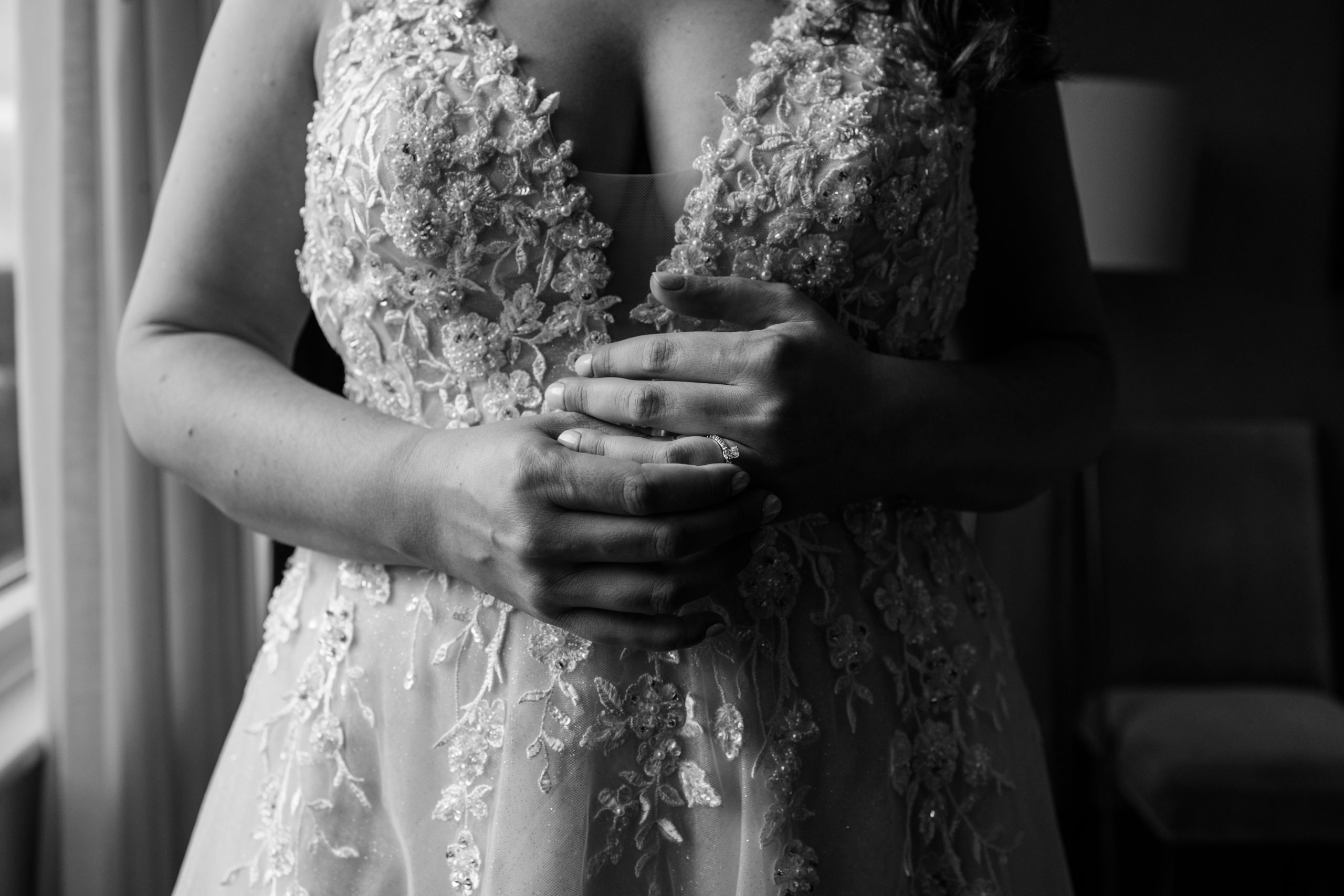 torso of woman in wedding dress, placing wedding ring on her own hand